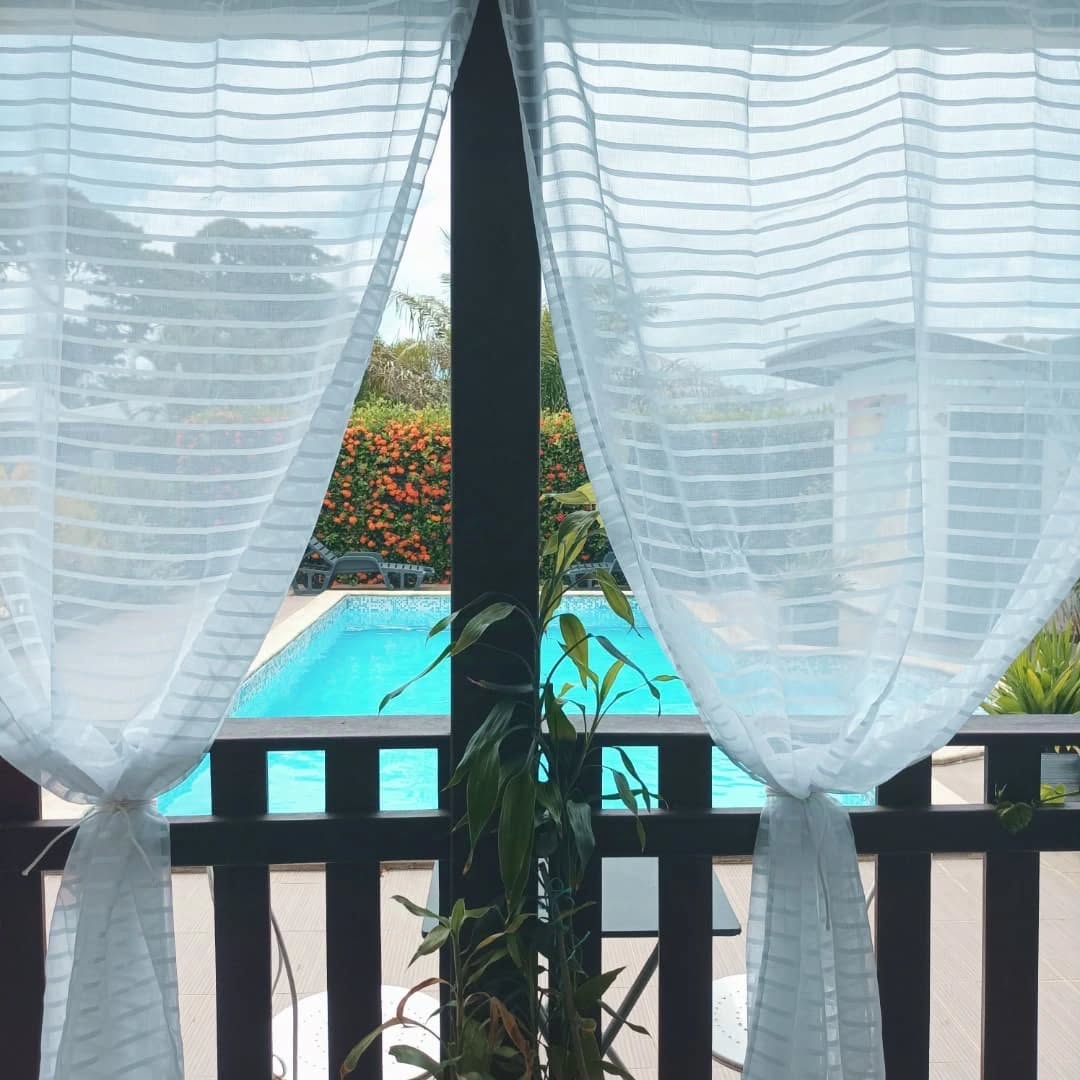 Vue sur la piscine depuis l'intérieur, rideaux légers